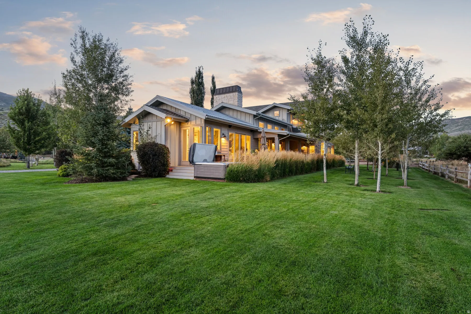 Extensive green lawn with mature trees and a wooden fence