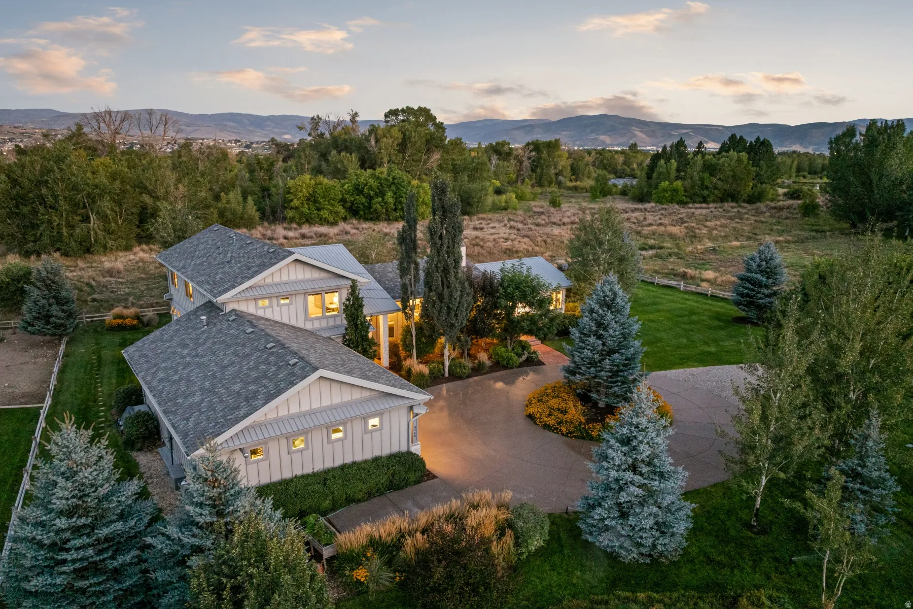 Spacious property featuring a large concrete driveway, mature landscaping, and a well-maintained lawn