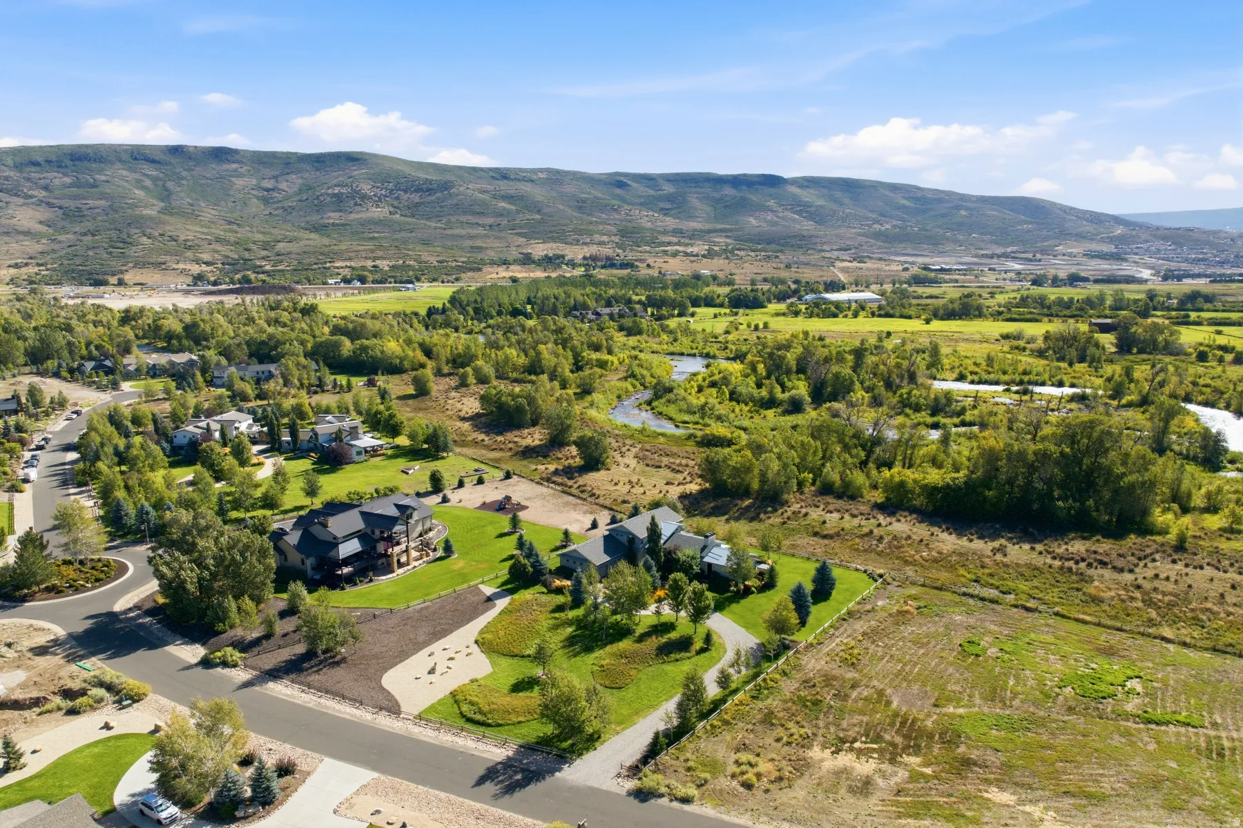 Expansive property with a verdant lawn, mature trees, and a winding river