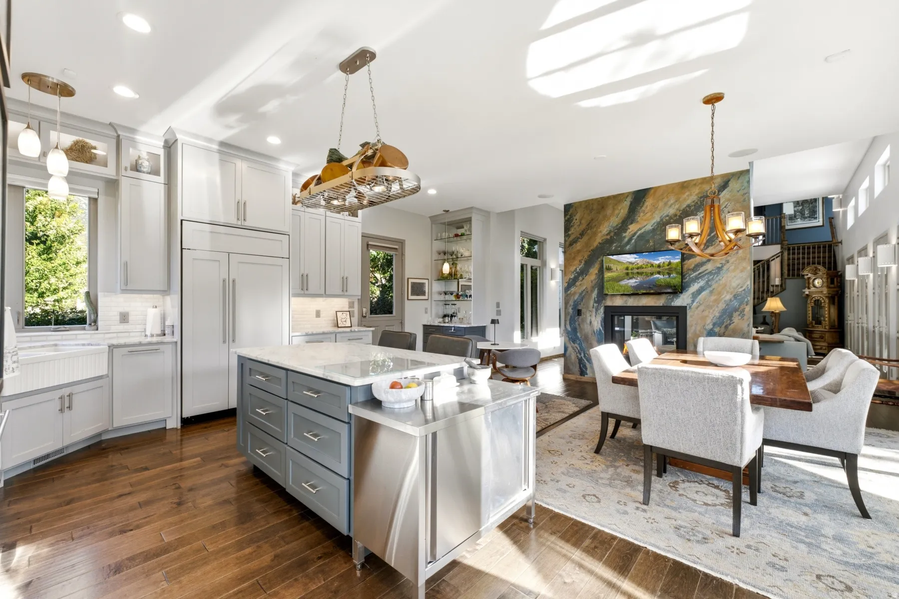 Gourmet kitchen with light gray cabinetry and integrated appliances, a central island with a white countertop, and wood-finish flooring