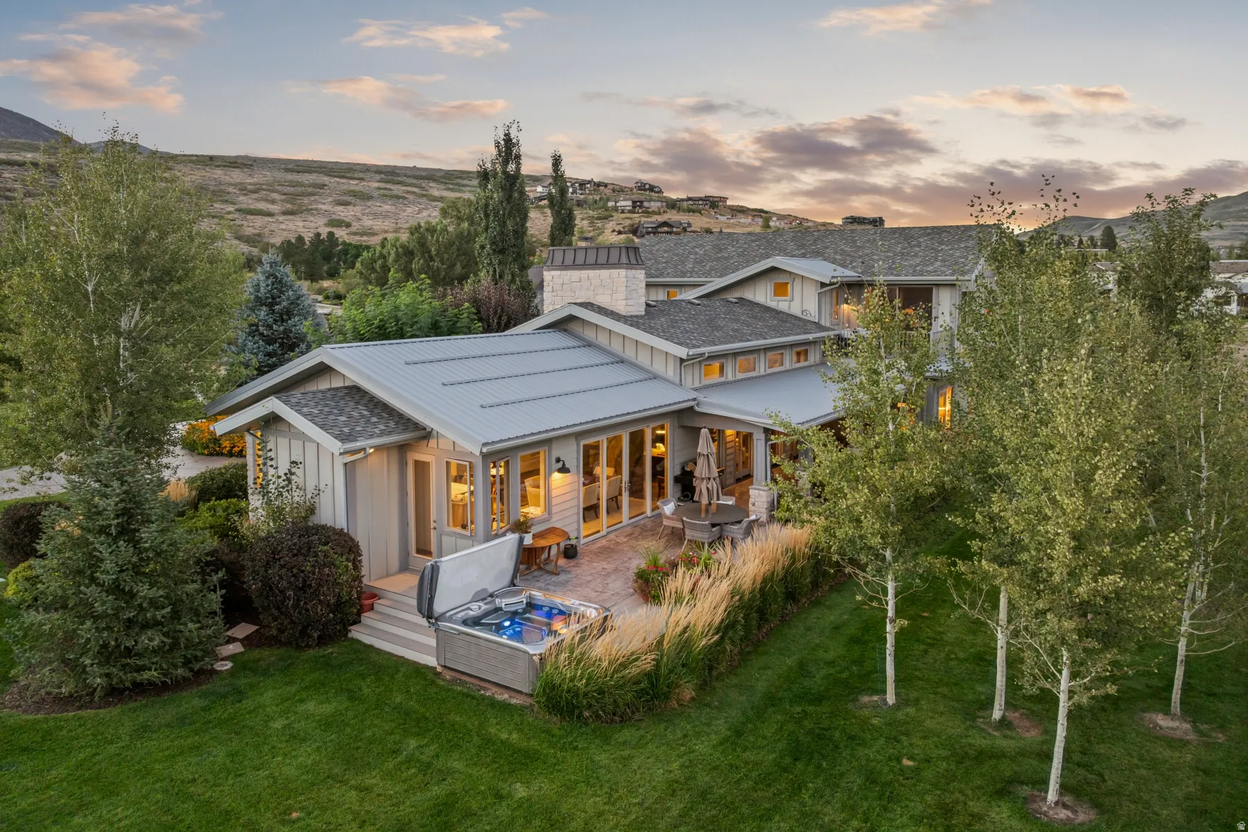 Expansive outdoor patio with a built-in spa, brick paving, and surrounding mature landscaping
