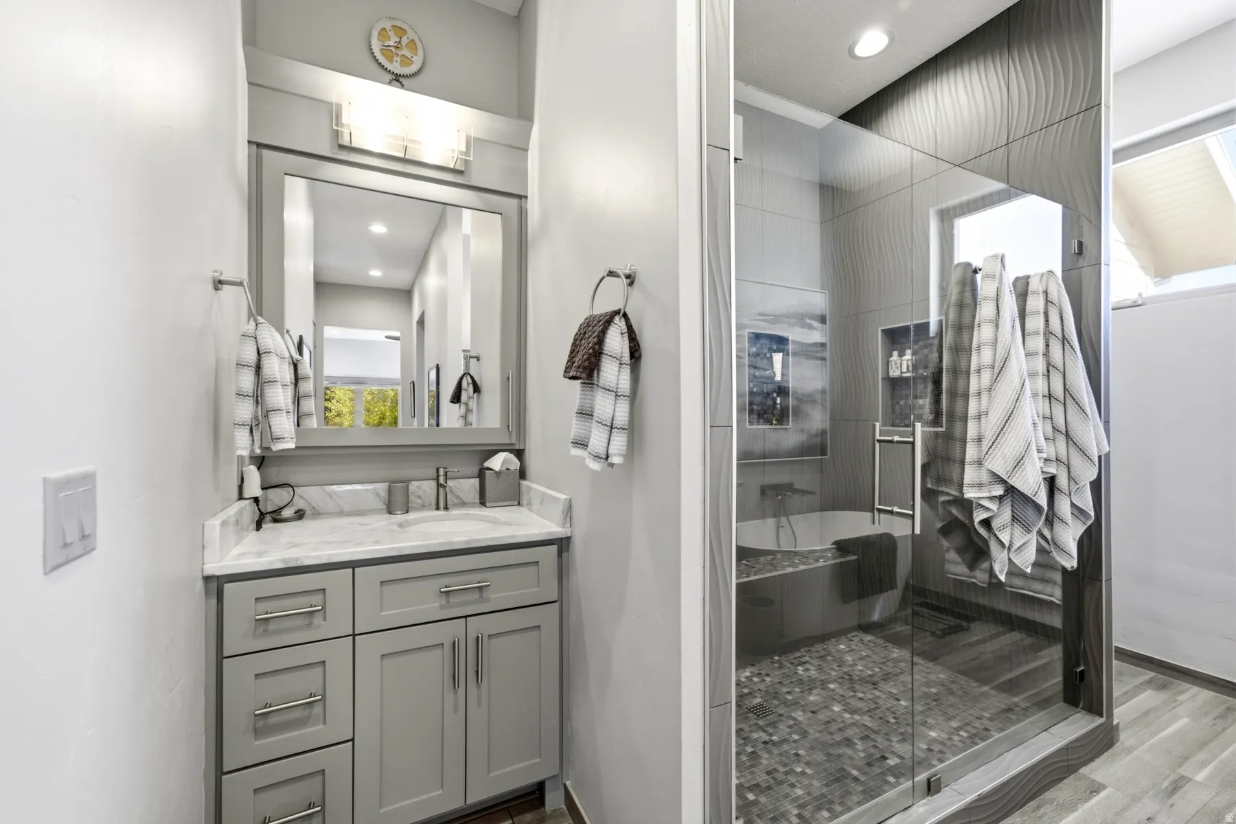 Vanity with grey cabinetry and marble-finish countertop, undermount sink, and chrome fixtures