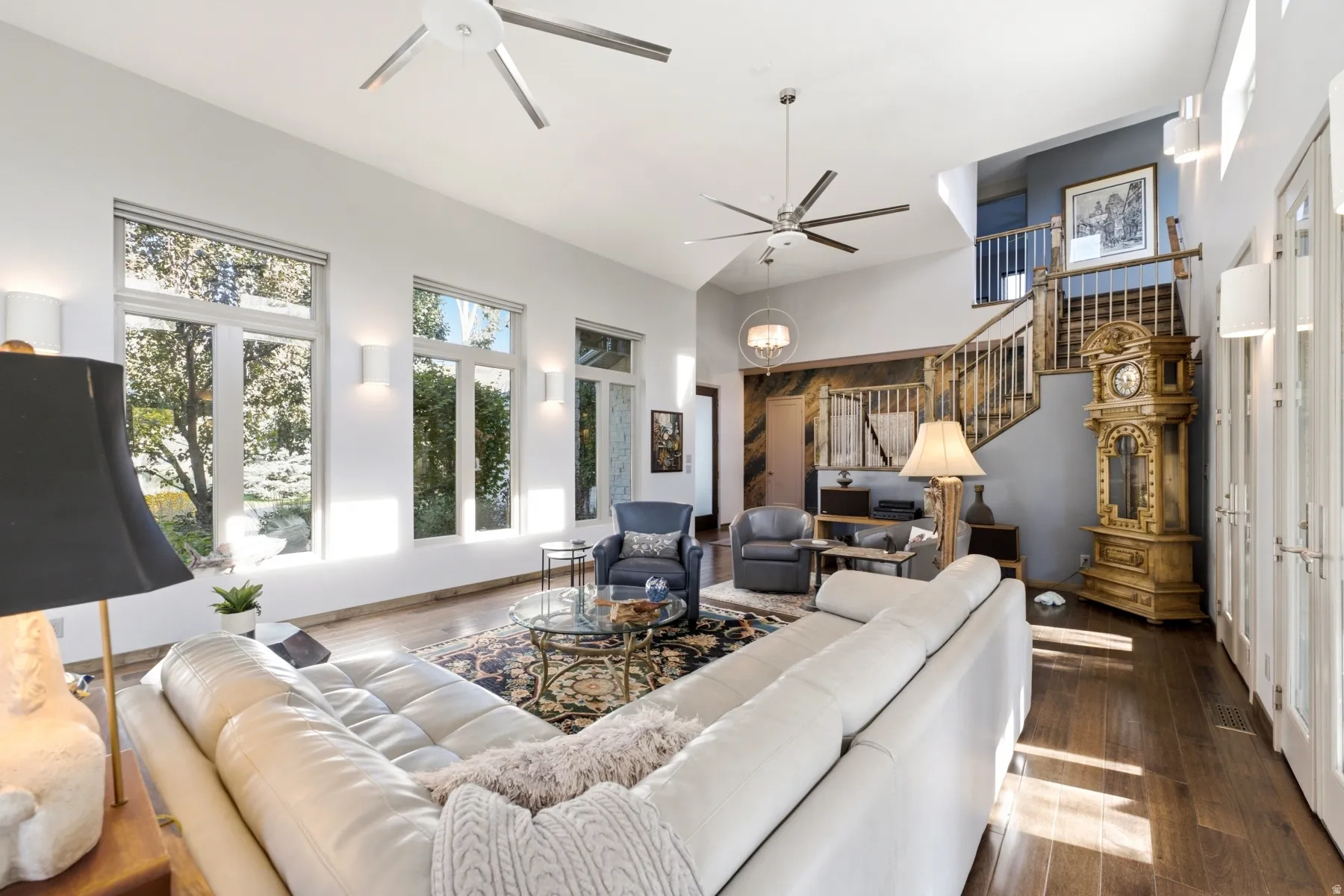 Hardwood flooring, high ceilings, multiple windows, double doors, and a staircase with wood banister