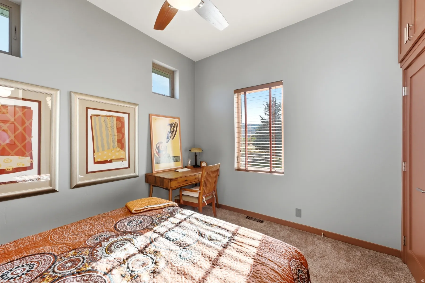 Carpeted room featuring high ceilings, a ceiling fan, and multiple windows