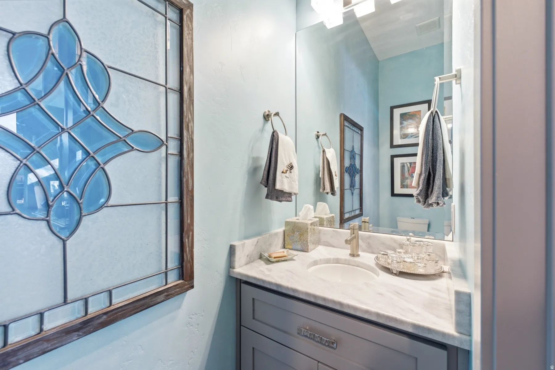 Built-in vanity with a single basin, stone countertop, and decorative framed mirror