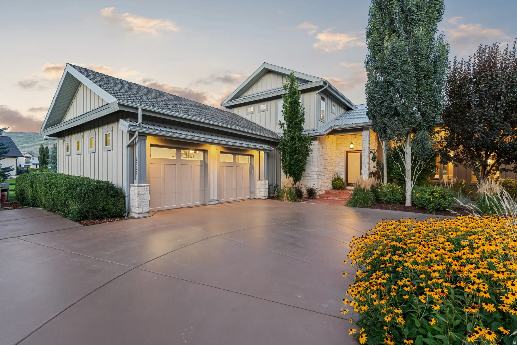 Stately home featuring stone accents, vertical siding, a multi-car garage, and a concrete driveway