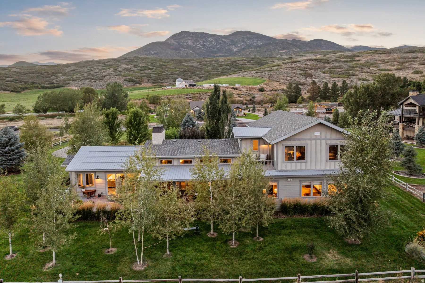 Contemporary architecture with board and batten siding, multiple gables, a metal roof, and a stone chimney