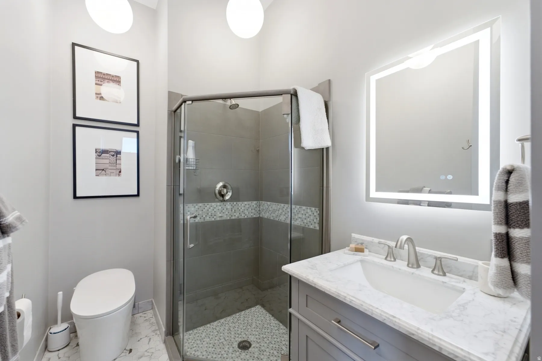 Glass-enclosed shower with tile surround and decorative accent band