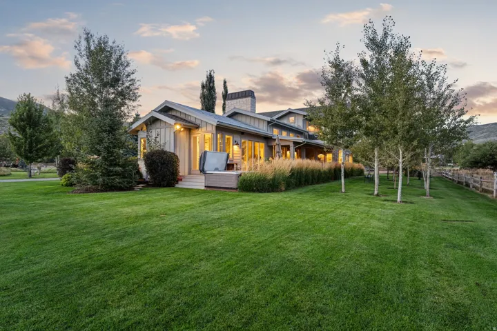 Extensive green lawn with mature trees and a wooden fence