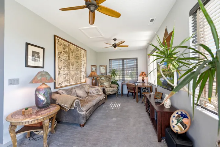 Two ceiling fans with wood-finish blades, multiple windows with horizontal blinds, and light gray wall paint