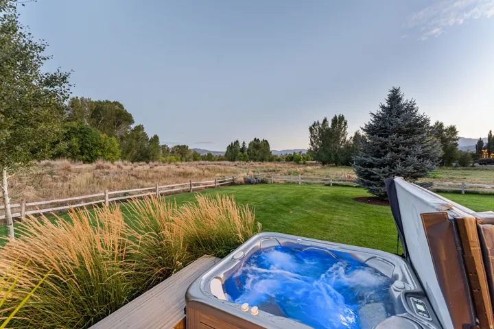 Outdoor spa with integrated lighting, surrounded by a manicured lawn and mature landscaping