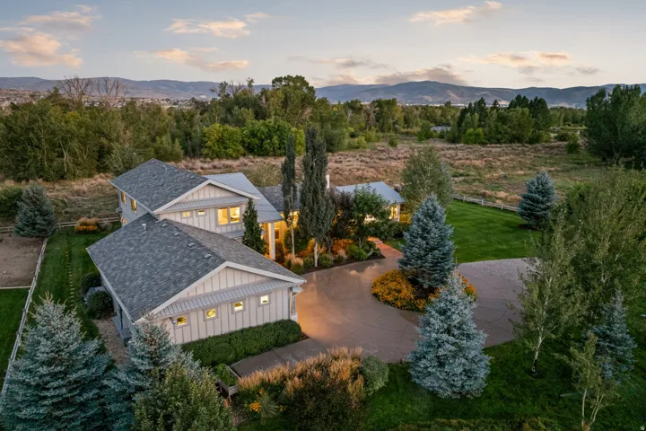 Spacious property featuring a large concrete driveway, mature landscaping, and a well-maintained lawn