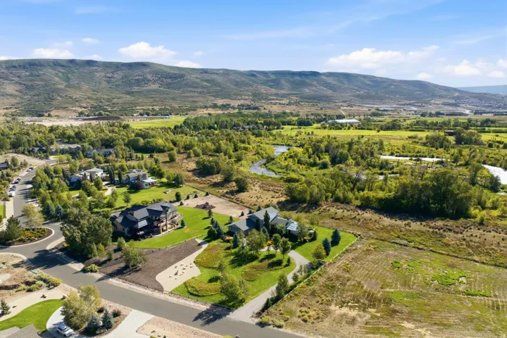 Expansive property with a verdant lawn, mature trees, and a winding river