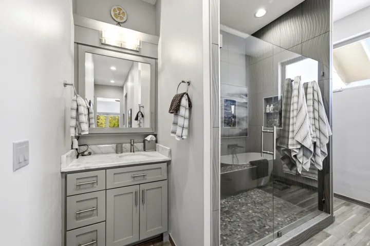 Vanity with grey cabinetry and marble-finish countertop, undermount sink, and chrome fixtures