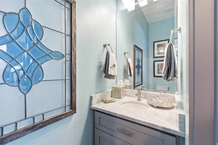 Built-in vanity with a single basin, stone countertop, and decorative framed mirror