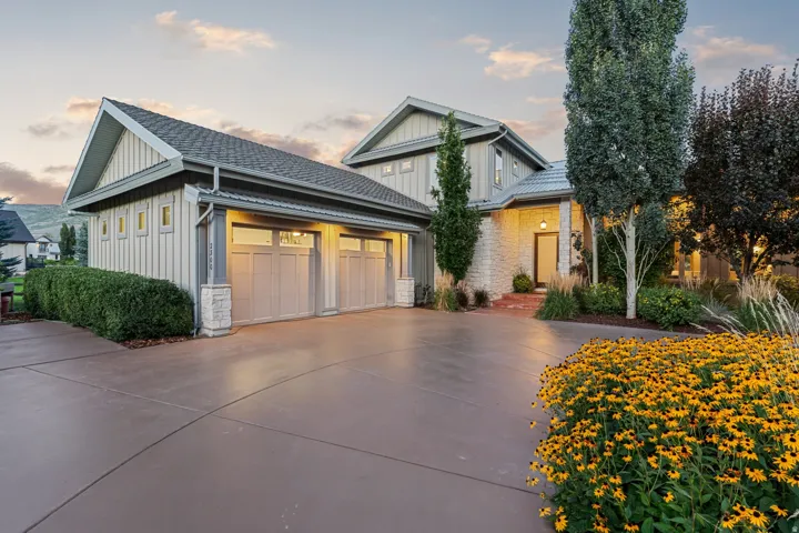 Stately home featuring stone accents, vertical siding, a multi-car garage, and a concrete driveway