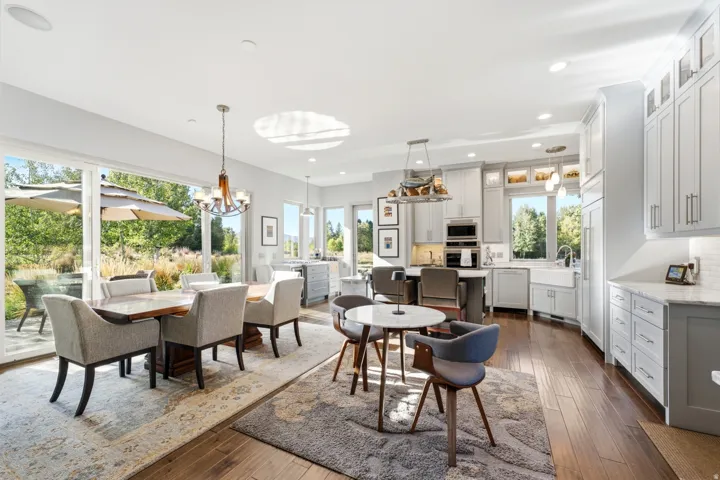 Expansive sliding glass doors, recessed ceiling lighting, wood-finish flooring, two-tone cabinetry, and a large farmhouse sink