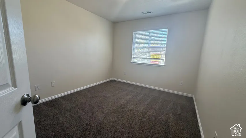 Neutral tone wall paint, textured carpeting, white trim, and a window with horizontal blinds