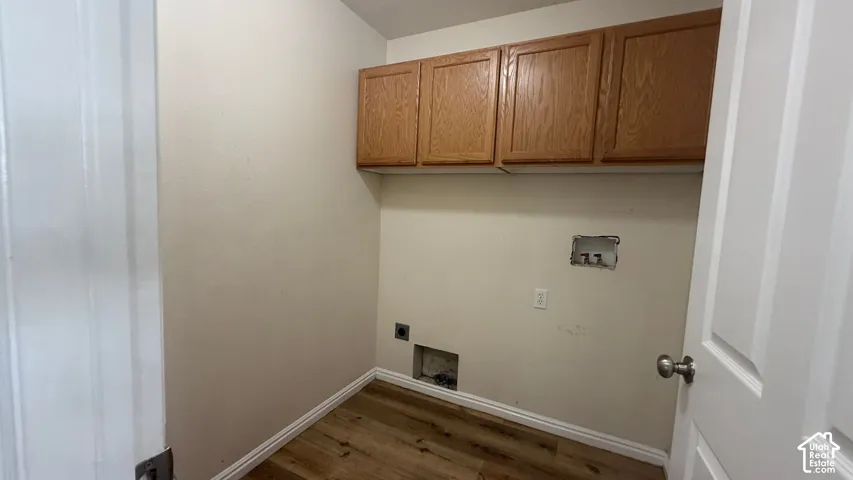 Laundry area with wood-finish flooring and upper cabinetry