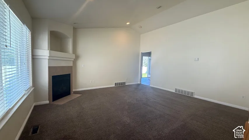 Carpeted living area with a built-in fireplace, tile surround, and an arched niche