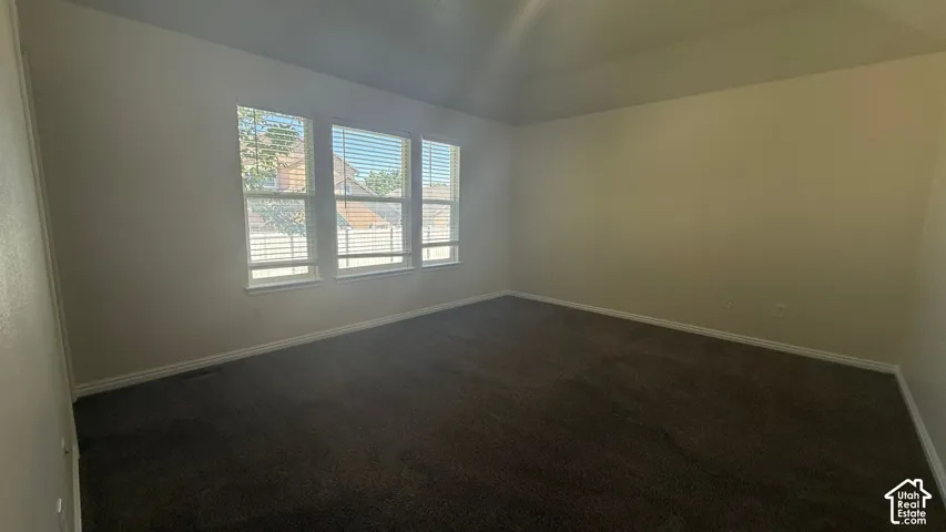 Tray ceiling room with three windows featuring blinds and dark carpeting