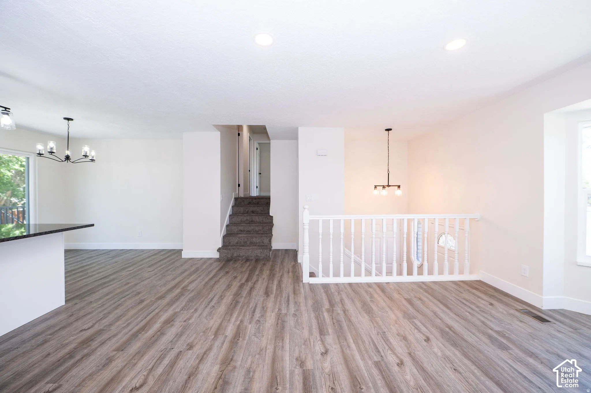 Wood-finish flooring, white walls, built-in staircase, white railing, and a window providing natural light