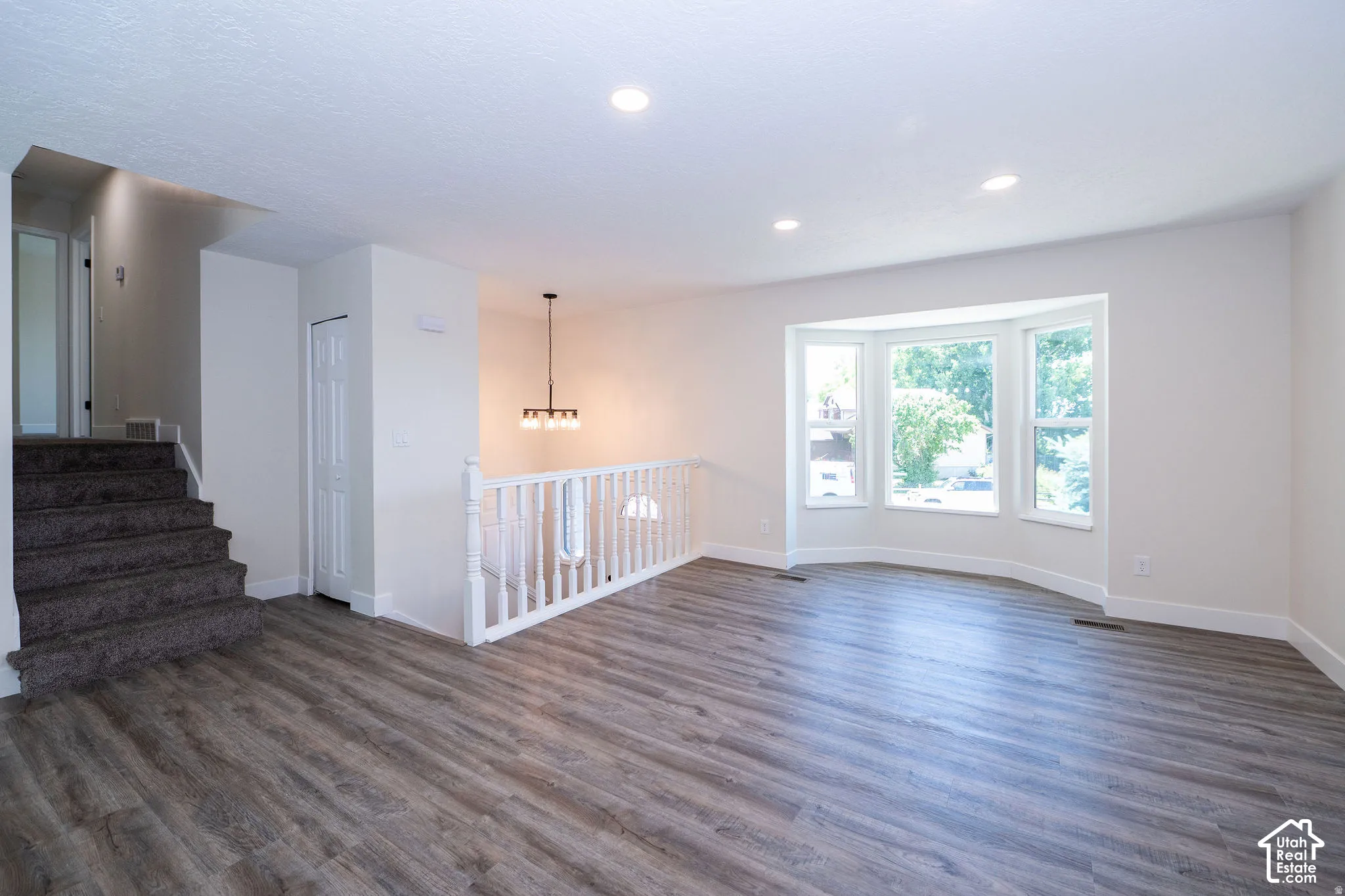 Wood-finish flooring, recessed lighting, and a prominent bay window