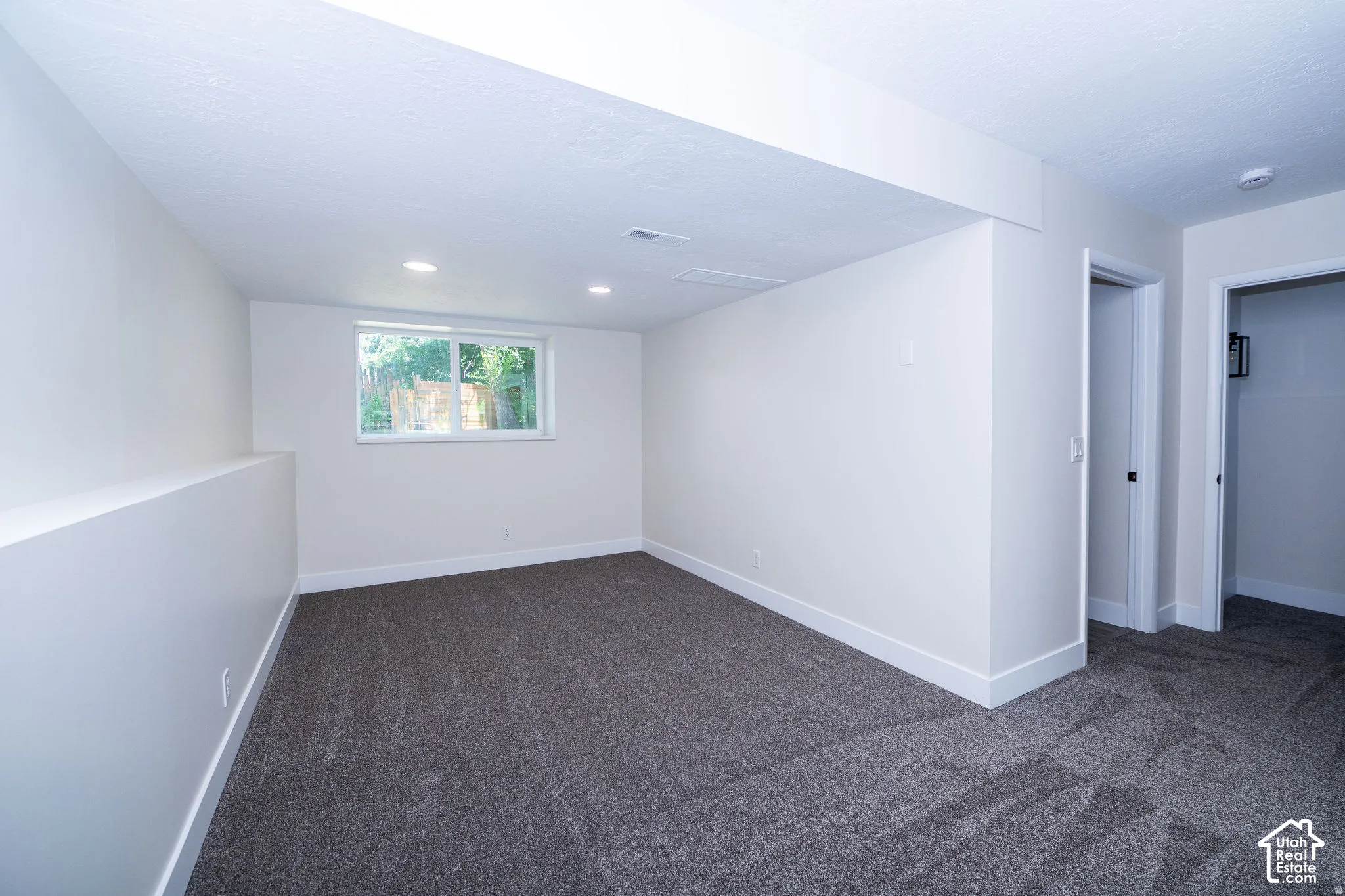 Recessed ceiling lighting, window with exterior scenery, painted walls, wall-to-wall carpeting, and white trim