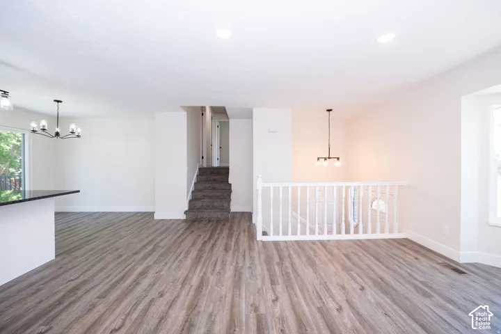 Wood-finish flooring, white walls, built-in staircase, white railing, and a window providing natural light