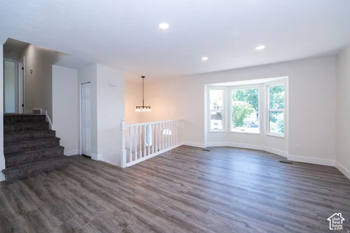 Wood-finish flooring, recessed lighting, and a prominent bay window