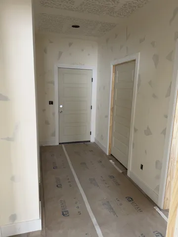 Interior hallway featuring neutral wall tones, two paneled doors with white trim, and a patterned ceiling texture