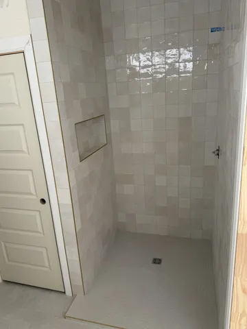 Tiled shower with a built-in niche, floor drain, and single shower control