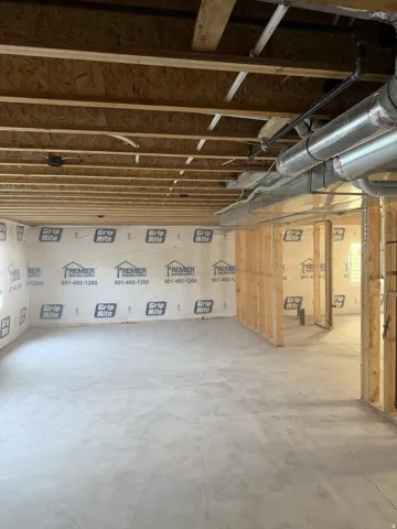 Unfinished lower level with concrete flooring, exposed wood framing, and visible ductwork