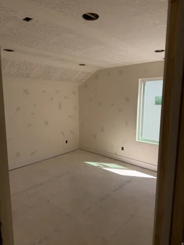 Unfinished room with textured ceiling, recessed lighting provisions, a single window, and a raw subfloor