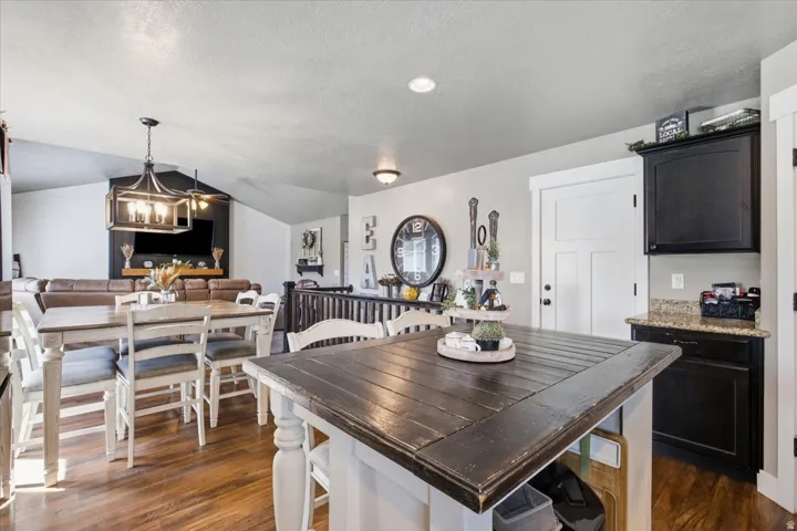 Wood-finish flooring throughout, vaulted ceiling, recessed lighting, built-in black cabinetry, and light-toned walls