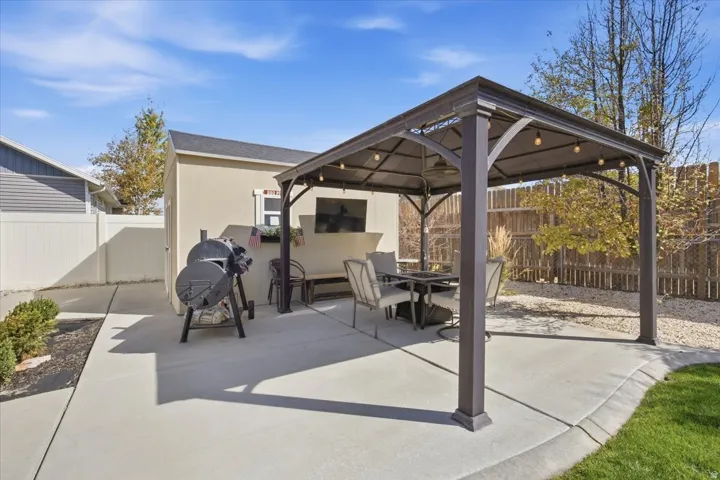 Paved patio with a permanent gazebo structure, an exterior storage shed, and an adjacent gravel area