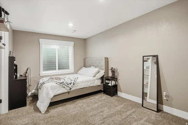 Plush carpet flooring, recessed ceiling lighting, and a single window with blinds