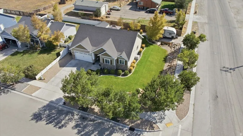 Craftsman-style exterior with stone and siding accents, attached two-car garage, landscaped front yard with mature trees, and concrete driveway