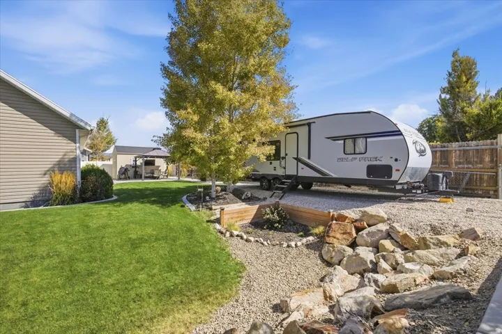 Expansive backyard featuring a manicured lawn, gravel area with rock landscaping, and a wood privacy fence