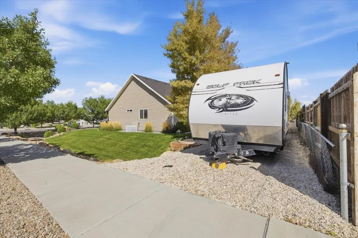 Expansive gravel-covered side yard with a full-height wood fence and a concrete driveway