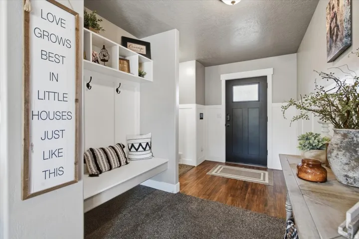 Entryway featuring wood-finish flooring and a built-in bench with integrated shelving and wall hooks