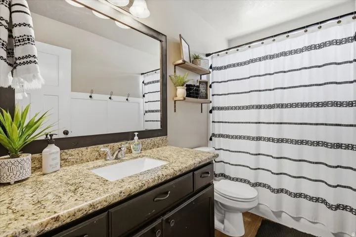 Vanity with light-colored stone countertop, undermount sink, and dark wood cabinetry
