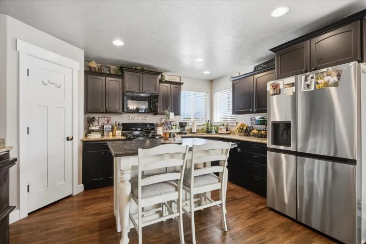 Kitchen featuring dark wood cabinetry, stainless steel appliances, a center island with a wood-finish countertop, recessed lighting, and wood-finish flooring