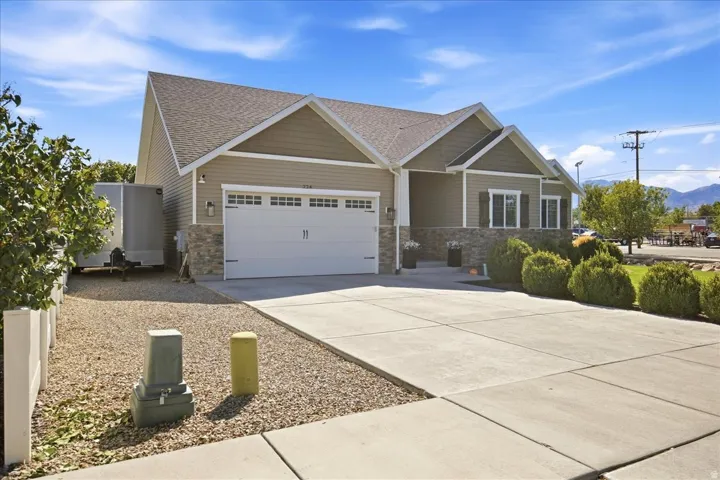 Exterior featuring horizontal siding, stone accents, a concrete driveway, a two-car garage, and mature landscaping