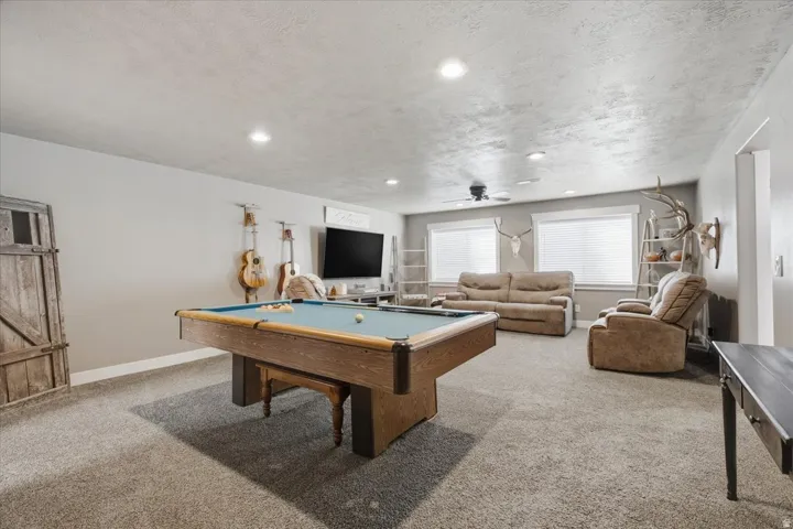 Spacious entertainment room featuring recessed lighting, a ceiling fan, and carpeted flooring