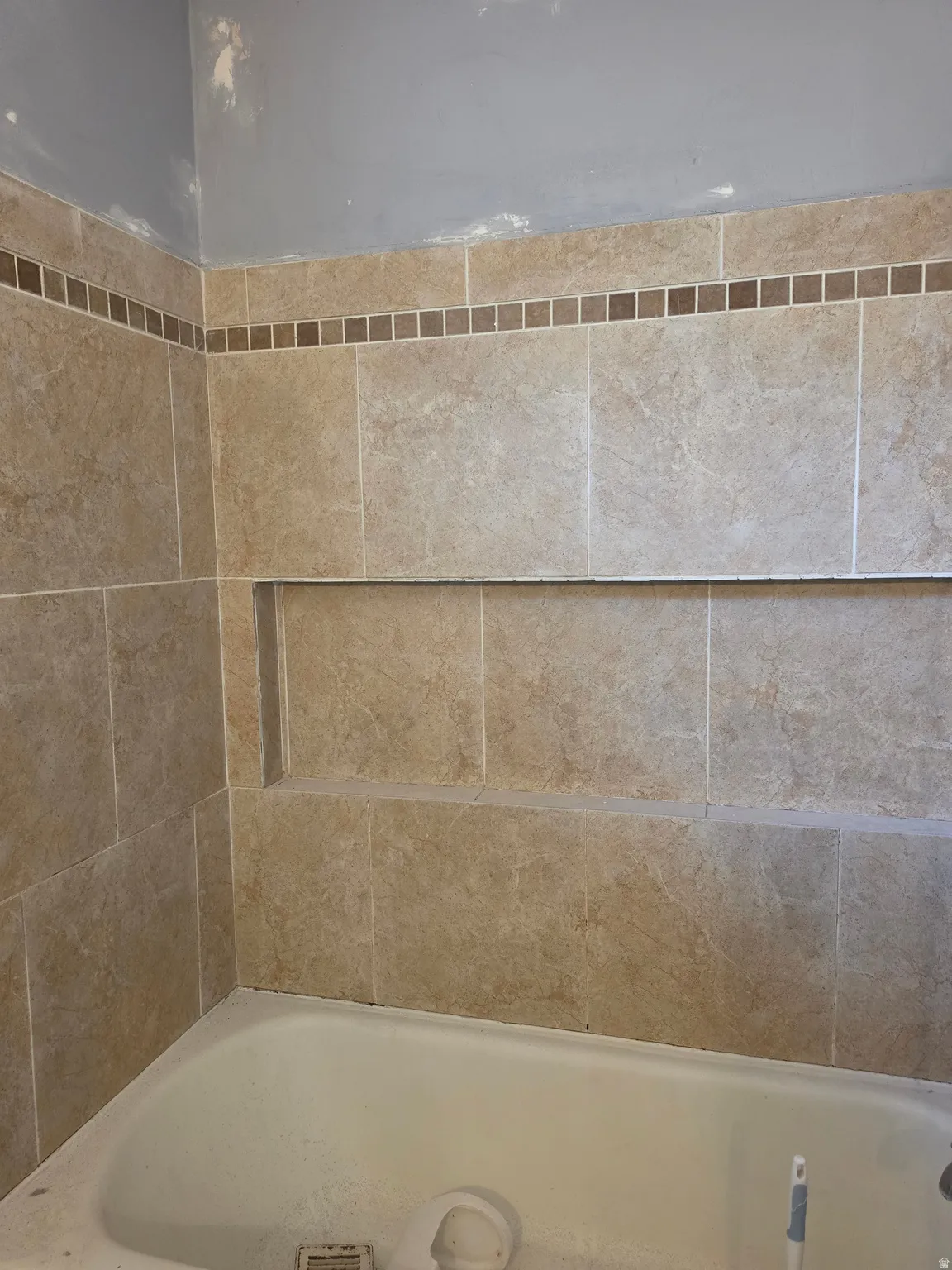 Tiled shower surround with an inset niche and decorative mosaic accent band