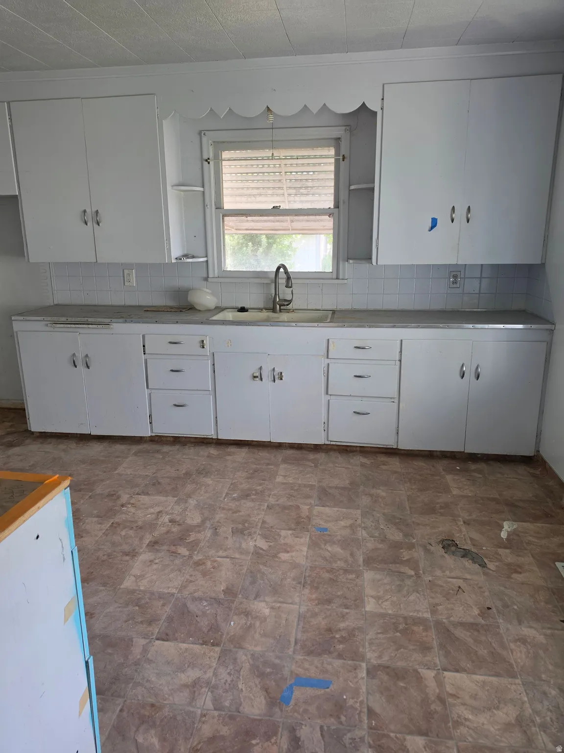 White cabinetry with ample storage, a stainless-steel gooseneck faucet, and a tiled backsplash