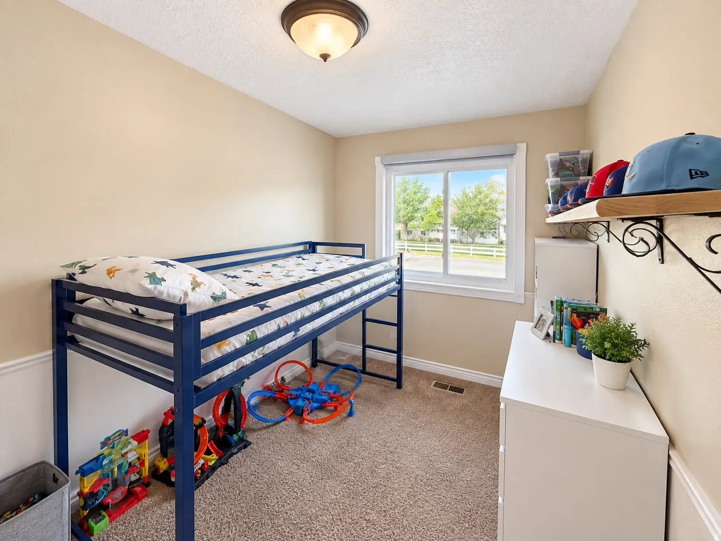 Neutral wall color, carpet flooring, window with white trim, wall-mounted light fixture, decorative wall shelving