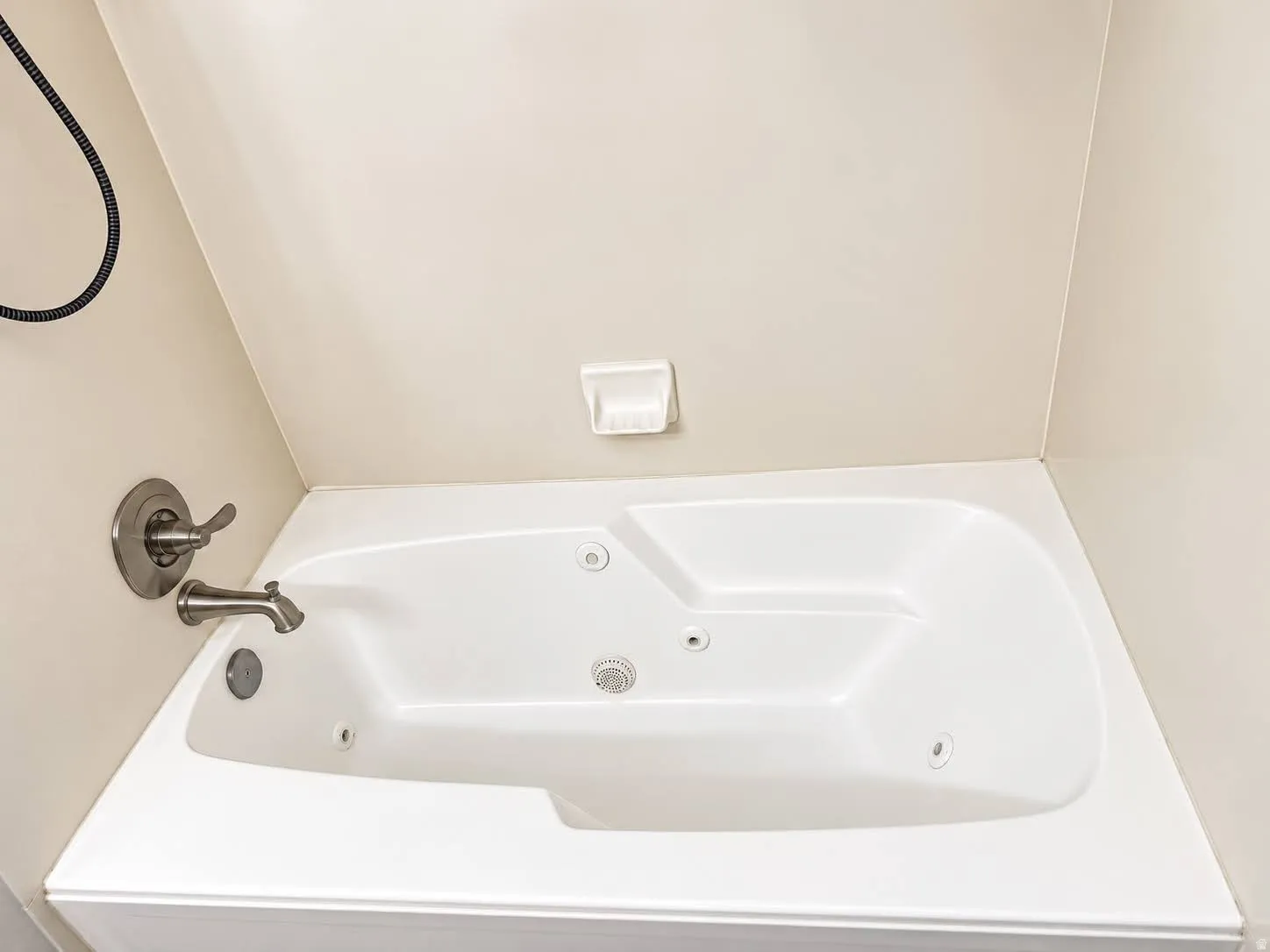 White jetted bathtub with a brushed nickel faucet and showerhead