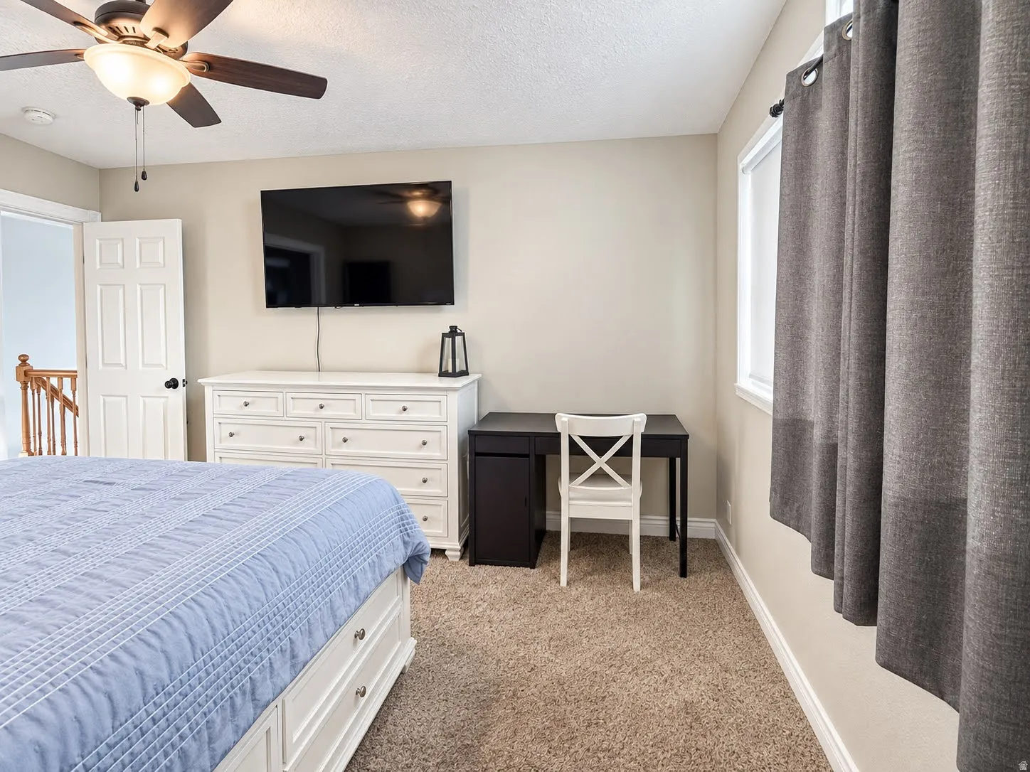 Neutral wall paint, ceiling fan, carpet flooring, window with white trim, and a white interior door